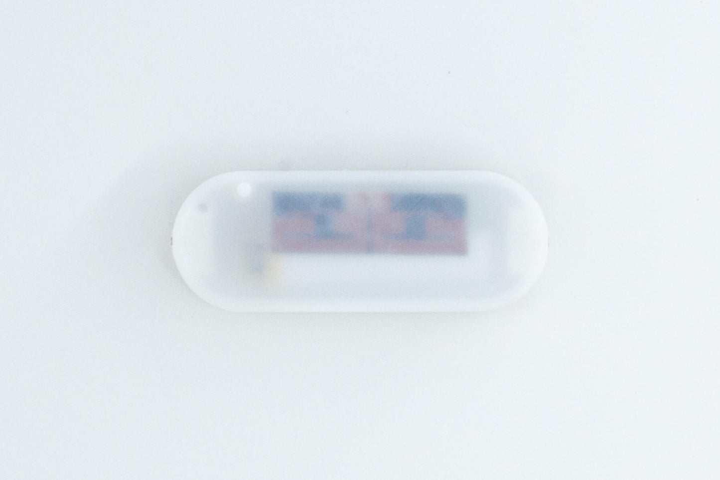 uECG ECG sensor, on white background, in a white 3D printed case, with visible snap electrode connectors (view from the top)